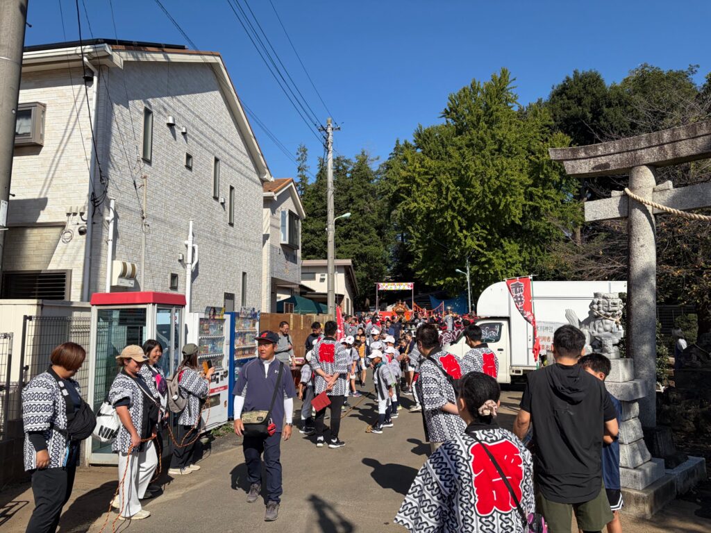 赤井氷川神社の鳥居の前で法被を着た人たちがにぎわう様子